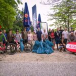 Eine Gruppe Mountainbiker mit aufgestapelten, gefüllten Müllsäcken, die vor ihnen liegen.