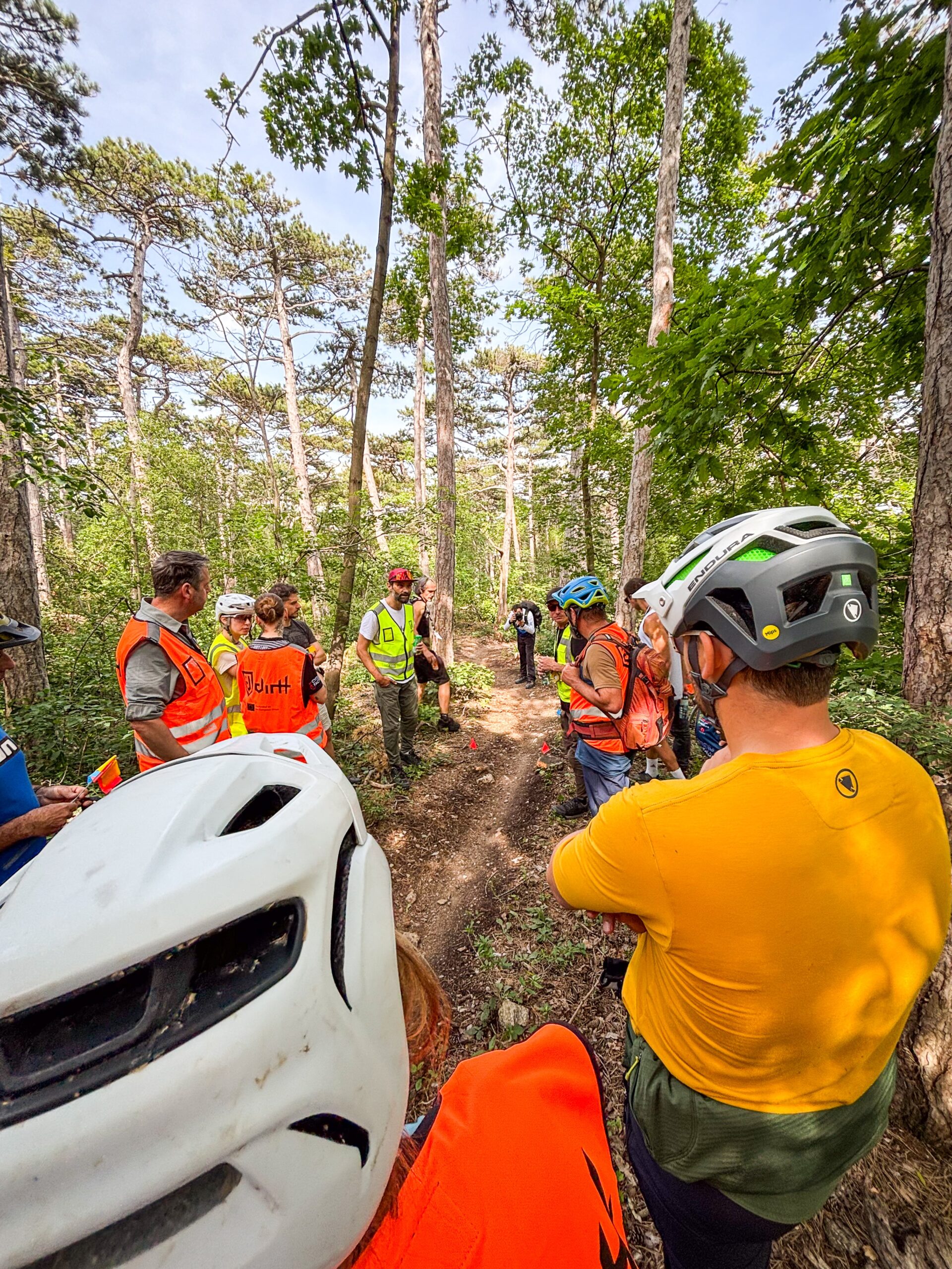 Eine Gruppe Mountainbiker:innen in Warnwesten auf einem Singletrail