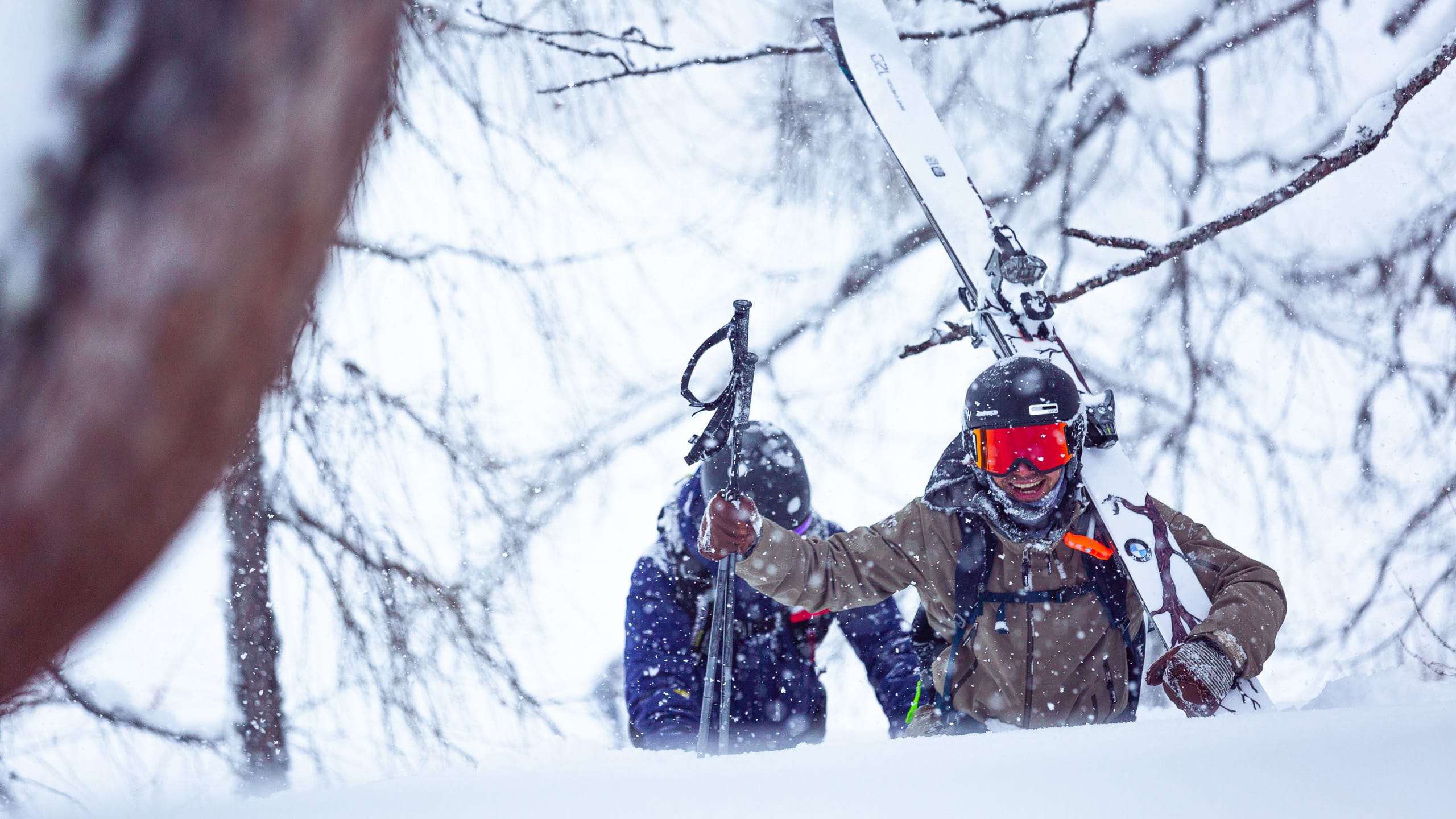 Ein Freerider trägt seine Ski durch den Schnee.